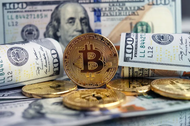 Ein Bitcoin neben Dollar-Noten.