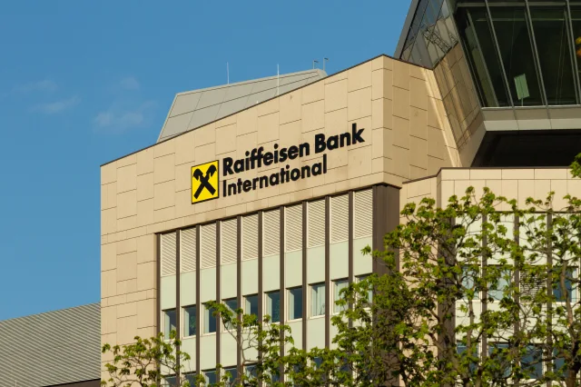 Das Bild zeigt die Zentrale der Raiffeisen Bank International (RBI) mit gut sichtbarem Unternehmenslogo an der Fassade eines modernen Bürogebäudes.