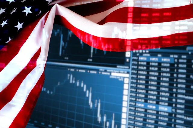 Eine US-Flagge vor einem Bildschirm mit Börsenkursen.