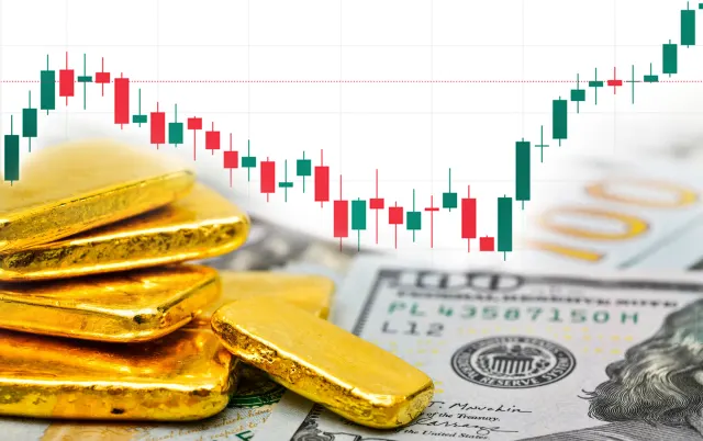 Goldbarren sind vor einem Kurschart zu sehen.