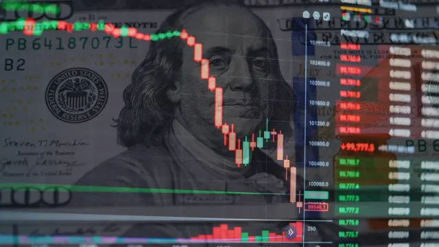 Ein Kurschart vor einer Dollar-Note.