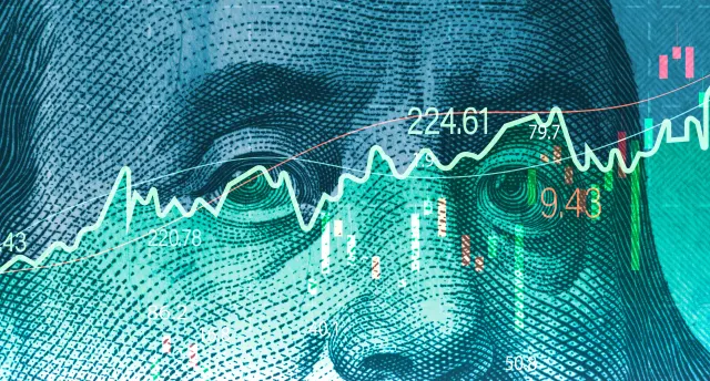 Ein Aktienkurs ist vor einem Dollar-Schein zu sehen.