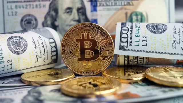 Ein Bitcoin neben Dollar-Noten.