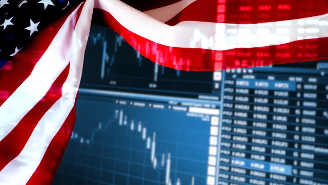 Eine US-Flagge vor einem Bildschirm mit Börsenkursen.