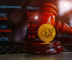 Ein Justizhammer sowie ein Bitcoin sind zu sehen.