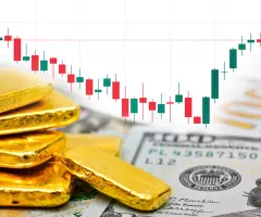 Goldbarren sind vor einem Kurschart zu sehen.