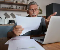 Ein Rentner sitzt fassungslos vor einem Laptop.