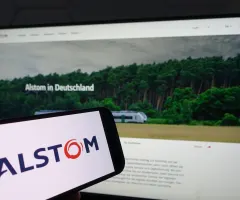 Smartphone mit dem Logo Alstom vor einem Bildschirm