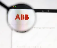 Zu sehen ist das ABB-Logo, das durch ein Brillenglas scharf dargestellt wird, während der Hintergrund unscharf bleibt. Das Bild symbolisiert den Schweizer Technologiekonzern und legt den Fokus auf dessen Markenlogo.
