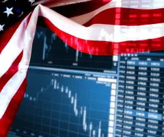 Eine US-Flagge vor einem Bildschirm mit Börsenkursen.